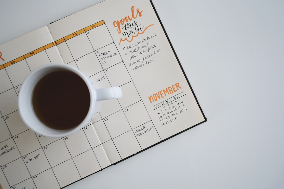 A white mug of black coffee sits on a handwritten monthly planner page headed November.
